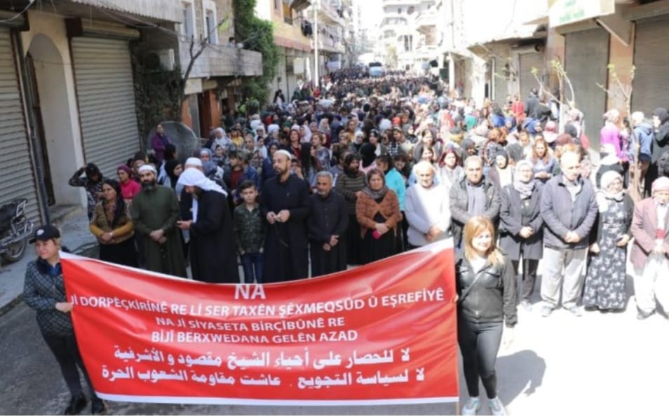 Protesters in Aleppo hold banner reading 'NO to the siege of Sheikh Maqsoud and Ashrafieh neighborhoods, NO to the starvation policy, long live the resistance of free people' (Wladimir Van Wilgenburg)