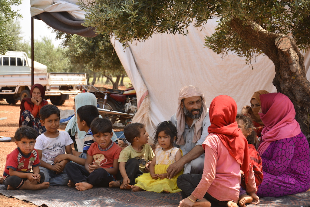 Abdul Aziz al-Kder, sitting with his wife and seven children under olive trees in random Camp on the road of Atme (Harun al-Aswad)