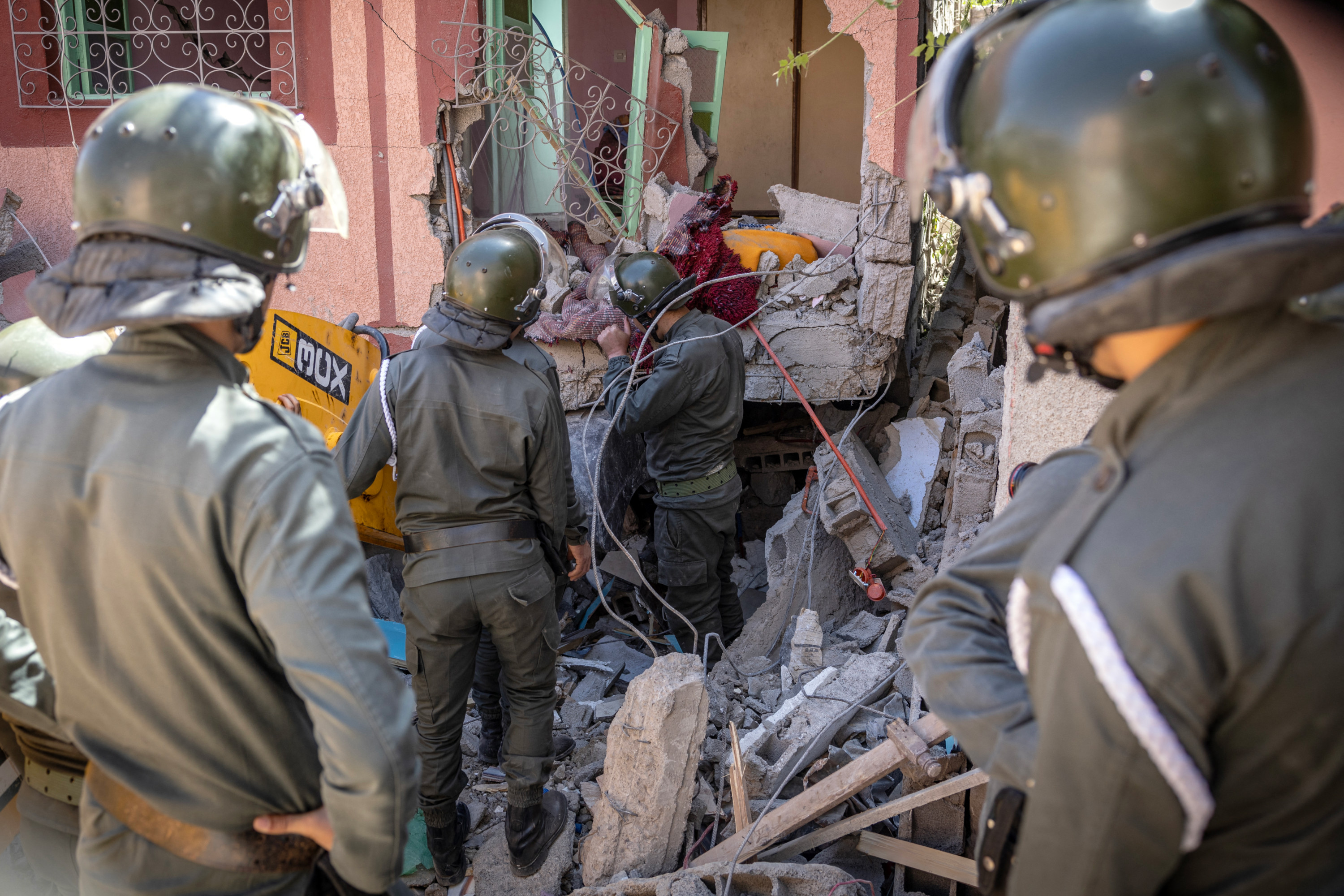 Rescuers use a small excavator to search for survivors under the rubble of a collapsed house in Moulay Brahim, Al Haouz province, on 9 September 2023 (AFP)