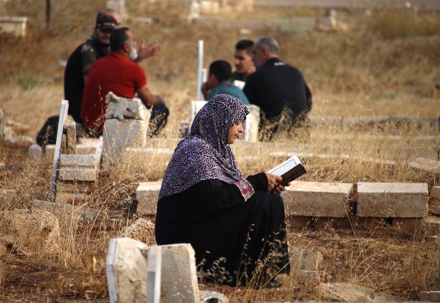 Une femme lit le Coran près de la tombe d’un parent à Deraa, en Syrie, le premier jour de l’Aïd al-Adha en août 2018 (AFP)