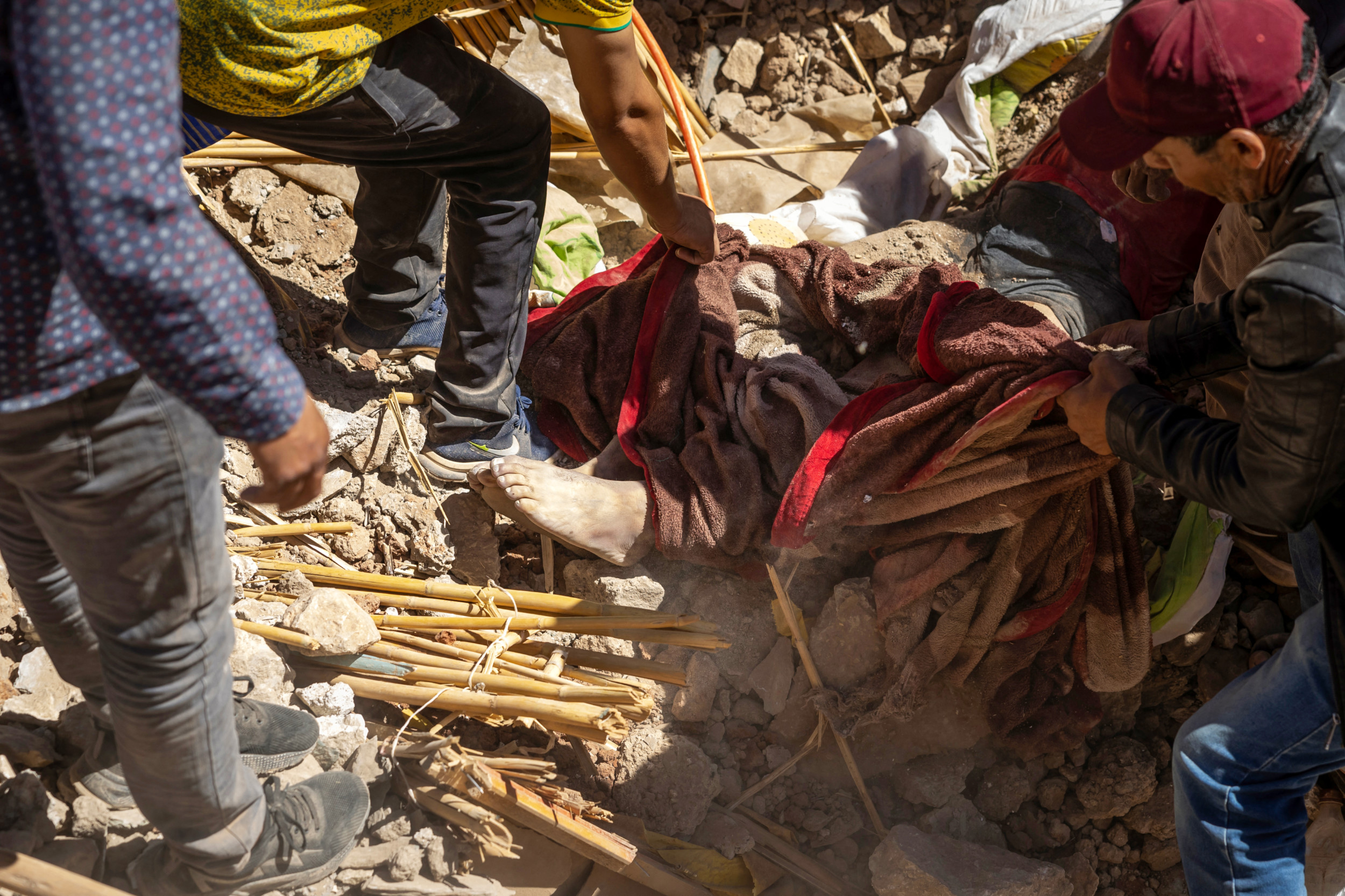 Volunteers recover a body from the rubble of collapsed houses in Tafeghaghte, 60 kilometres southwest of Marrakesh, on 10 September 2023 (AFP)