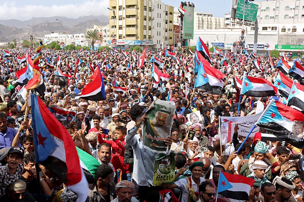 Un homme brandit une affiche représentant le roi Salmane d’Arabie saoudite au milieu d’un rassemblement de partisans d’une faction des séparatistes du sud du Yémen agitant des drapeaux de l’ancien Yémen du Sud (AFP)