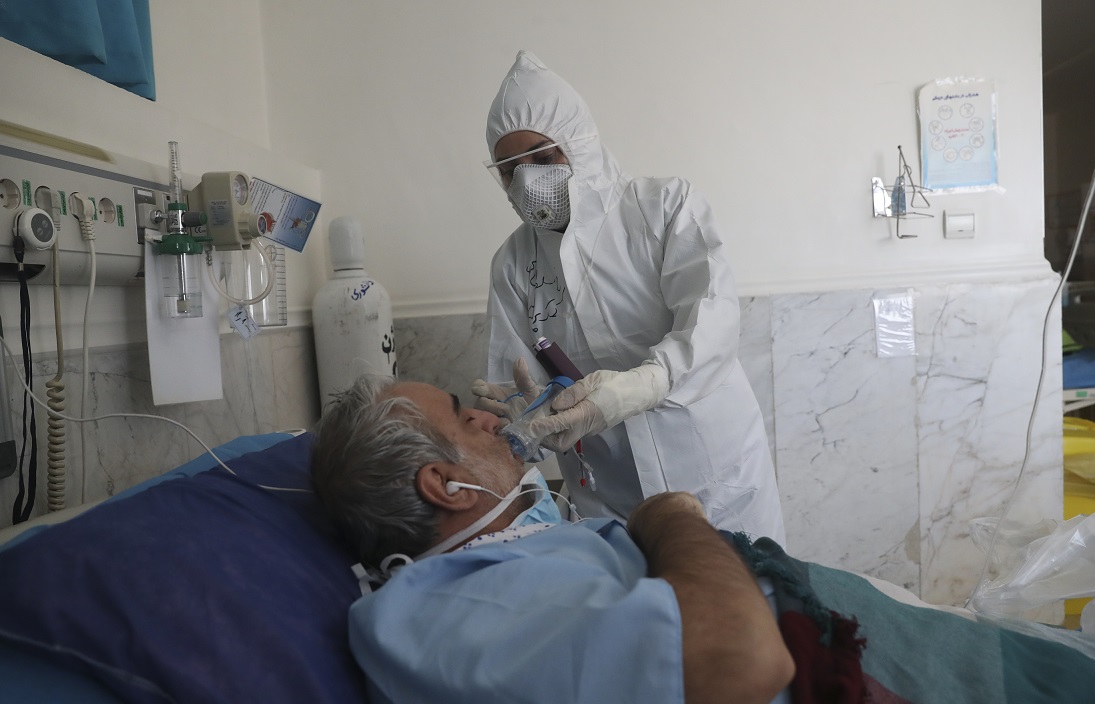 Une infirmière du service des maladies infectieuses de l’hôpital Masih Daneshvari aide un patient du COVID-19 à s’oxygéner (MEE/Mohammadreza Abbasi)