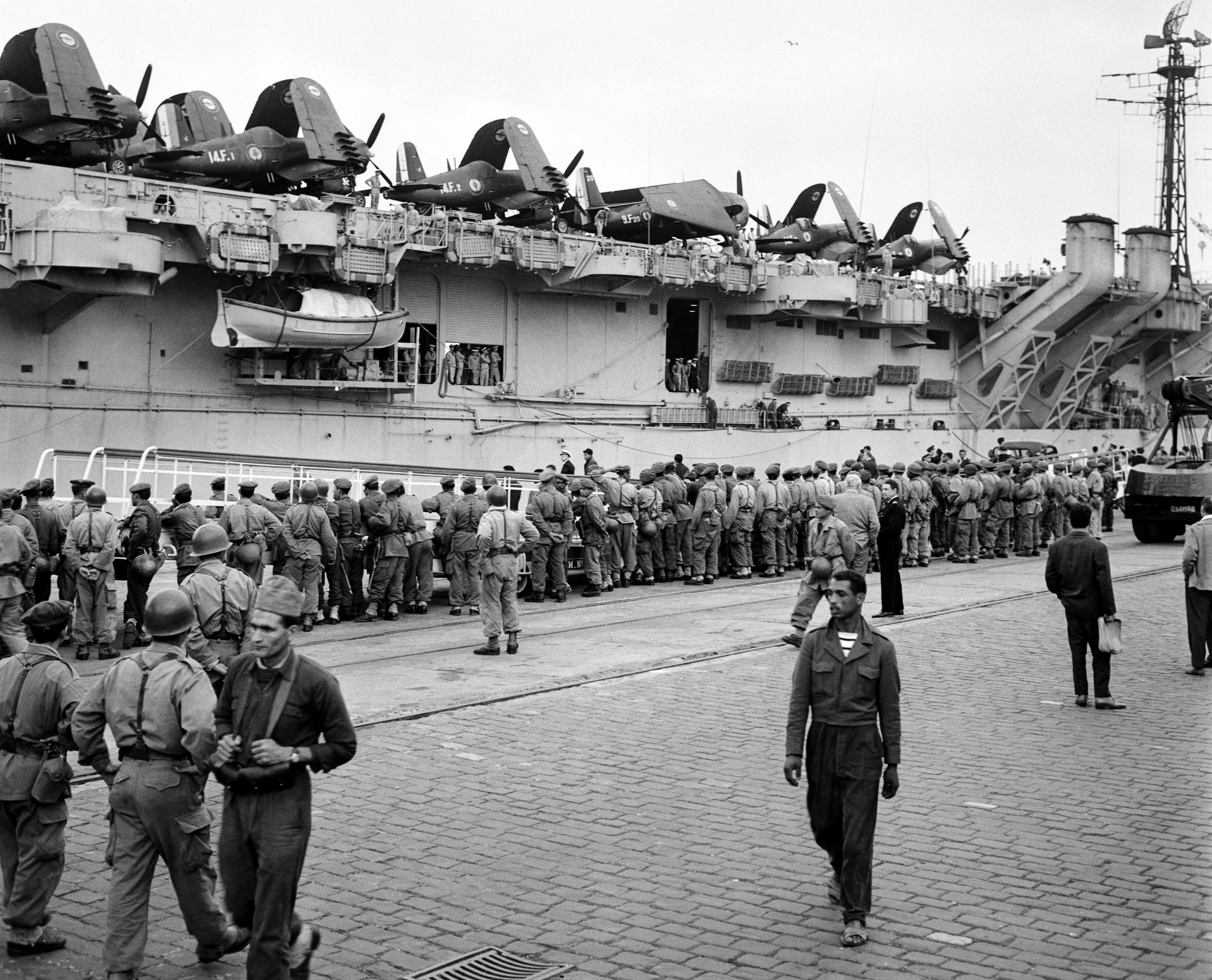 Des marins français et des soldats marocains patientent à côté du porte-avions La Fayette après le séisme meurtrier d’Agadir, le 4 mars 1960 (AFP)