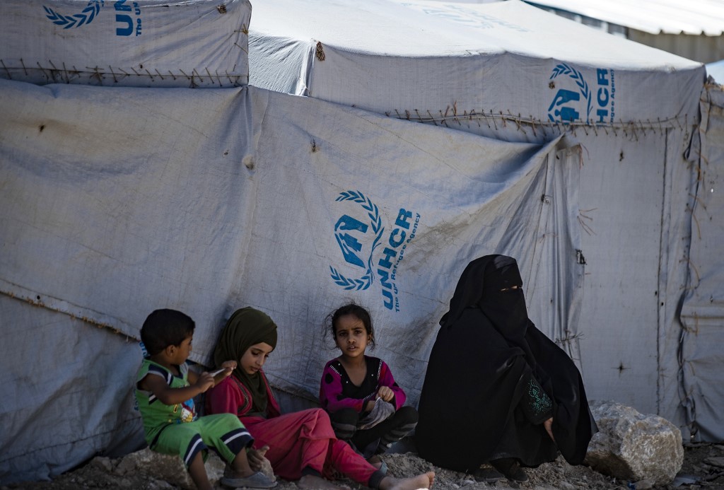 Members of a displaced family sit outside a tent in Syria’s al-Hol camp on 25 August (AFP)