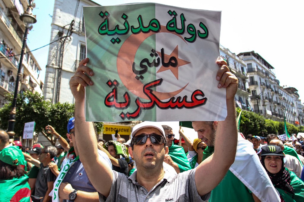 An Algerian protester holds a sign reading ‘civilian, not military, state’ on 19 July (AFP)