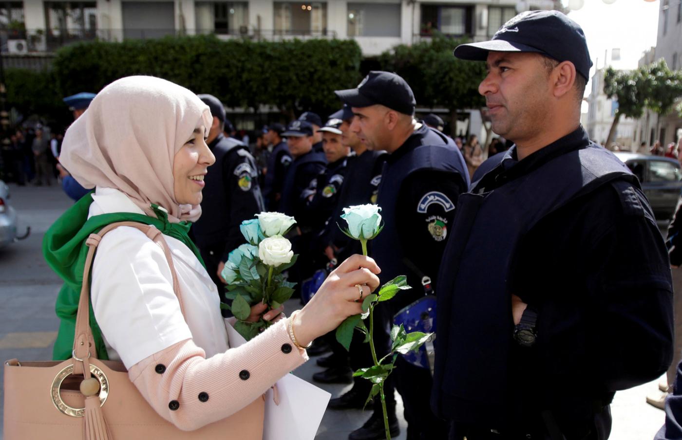 An Algerian protester offers roses to police during protests by teachers, lawyers and officials in several cities across the country on Wednesday, 13 March (Reuters)