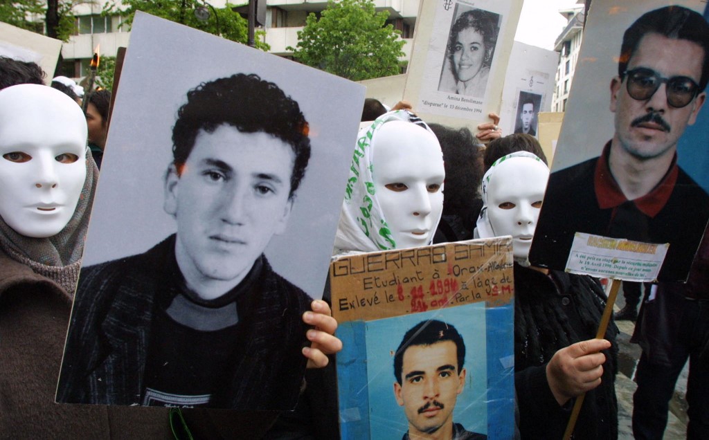 Des personnes, appartenant pour la plupart au collectif des familles de disparus en Algérie, manifestent, avec des masques blancs pour symboliser les disparus, le 25 avril 2001 devant le Centre culturel algérien à Paris, contre la présence à Paris du général algérien Khaled Nezzar (Thomas Coex/AFP)