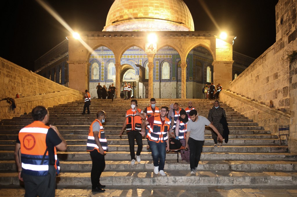 Palestinian medics evacuate a wounded person at Jerusalem’s al-Aqsa Mosque on 10 May 2021 (AFP)