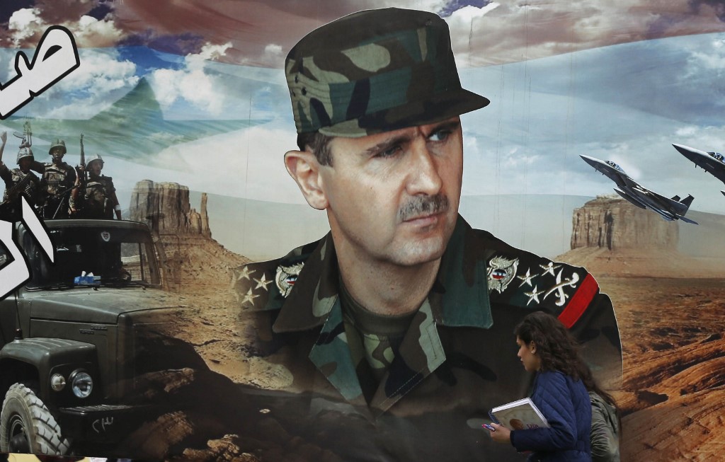 A Syrian woman walks past a portrait of President Bashar al-Assad in Damascus on 14 March (AFP)