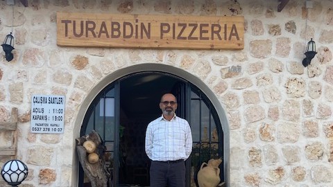 mAziz Demir pose devant sa pizzeria à Midyat, en Turquie, en octobre 2023 (Mehmet Algan/MEE)
