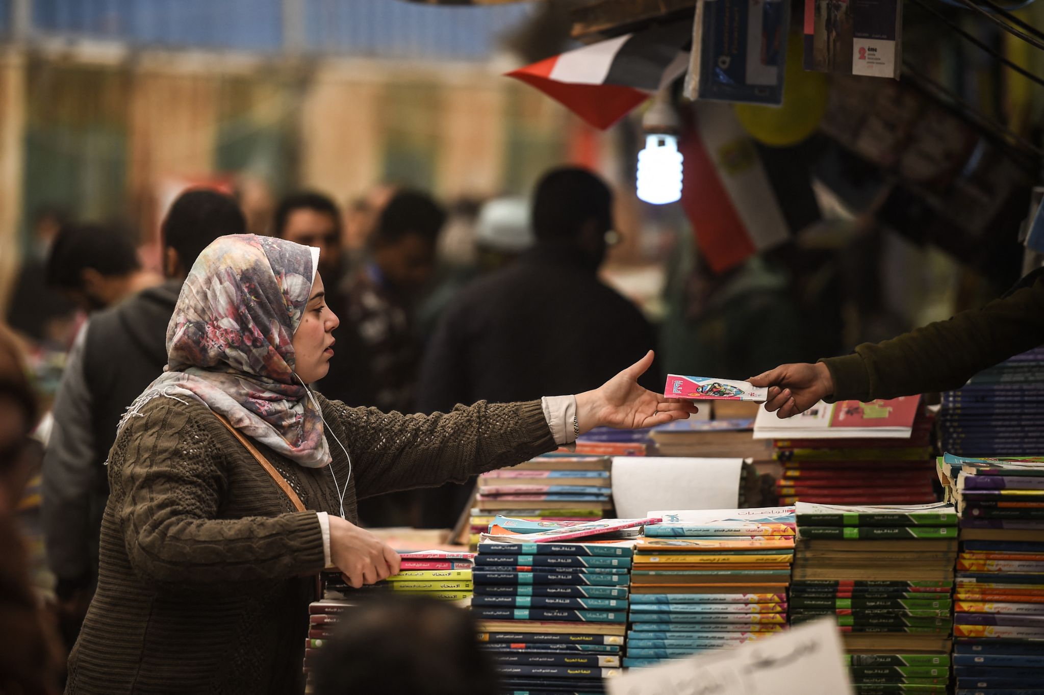 A woman is handed a book at Cairo's historic al-Azbakeya book market at downtown in Cairo (AFP/Mohamed el-Shahed)