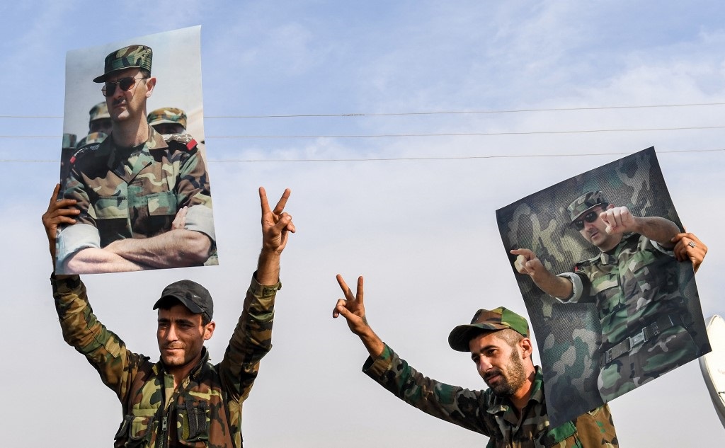 Syrian government soldiers hold up portraits of President Bashar al-Assad on the outskirts of the northern city of Manbij last week (AFP)