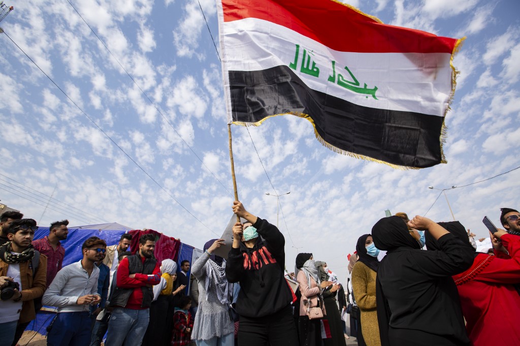 An Iraqi student waves the national flag during an anti-government demonstration in Basra on 31 December (AFP)