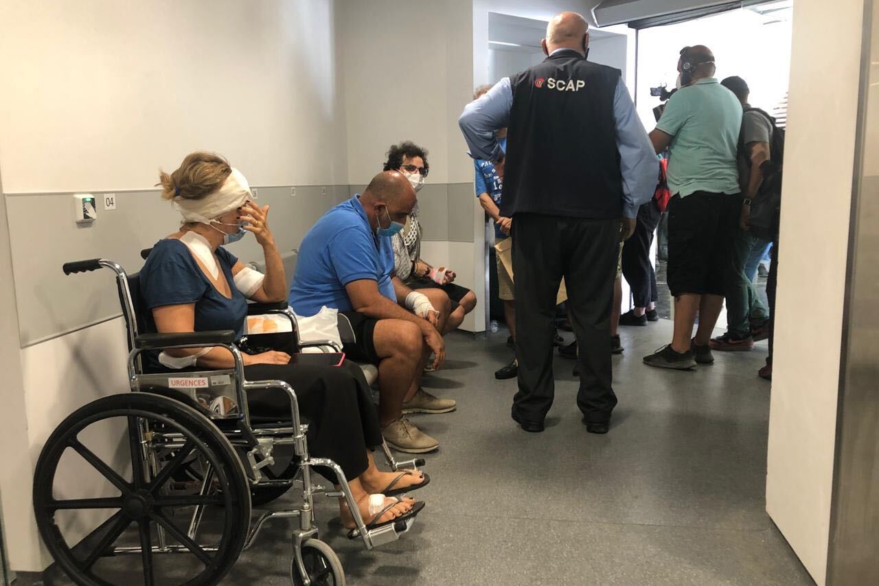 Patients with visible injuries sit down after being treated at Hotel Dieu de France.