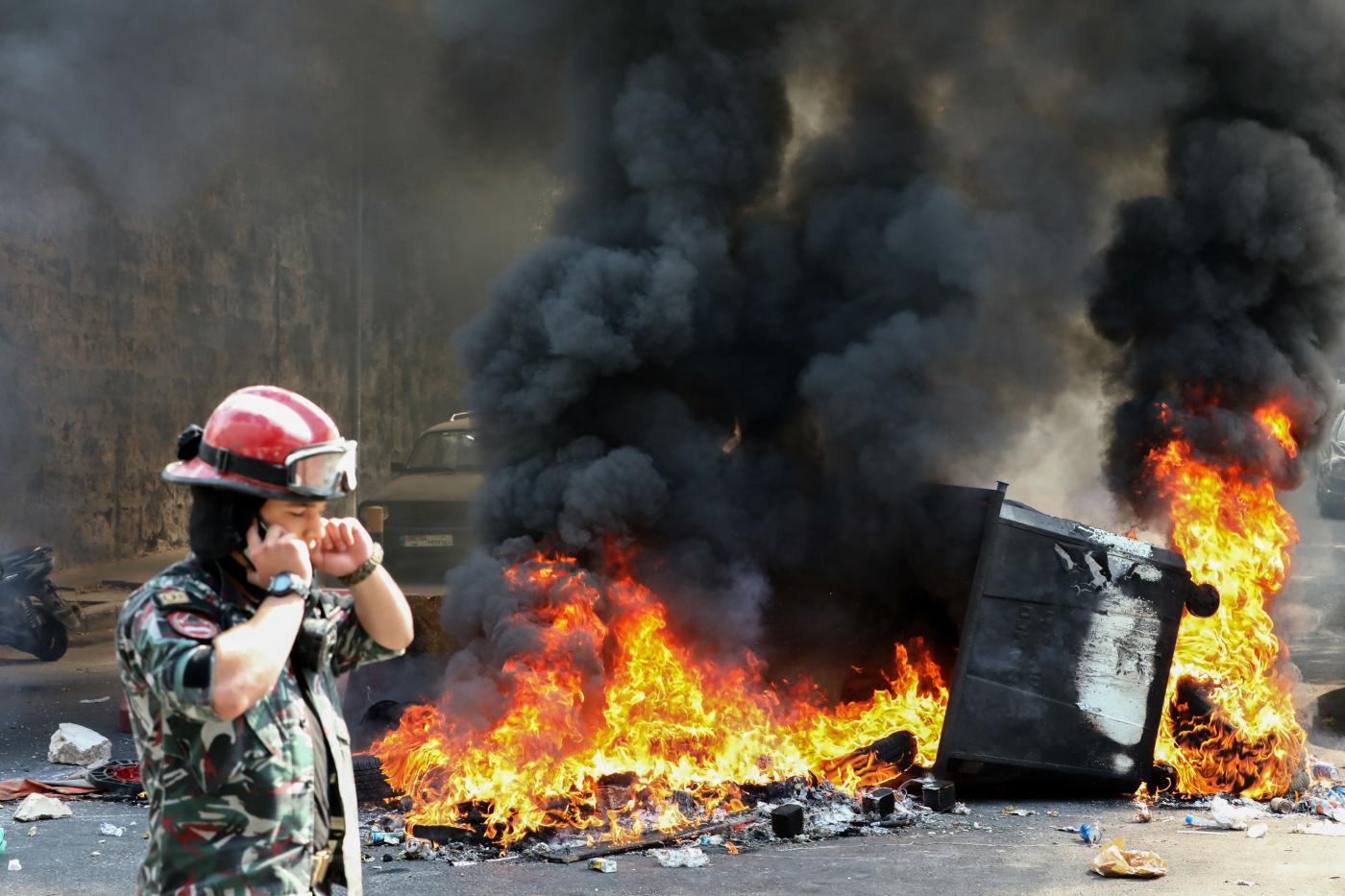 Un pompier libanais passe devant une benne à ordures incendiée lors d’une manifestation sur la place des Martyrs, dans le centre de Beyrouth, le 29 septembre (AFP)