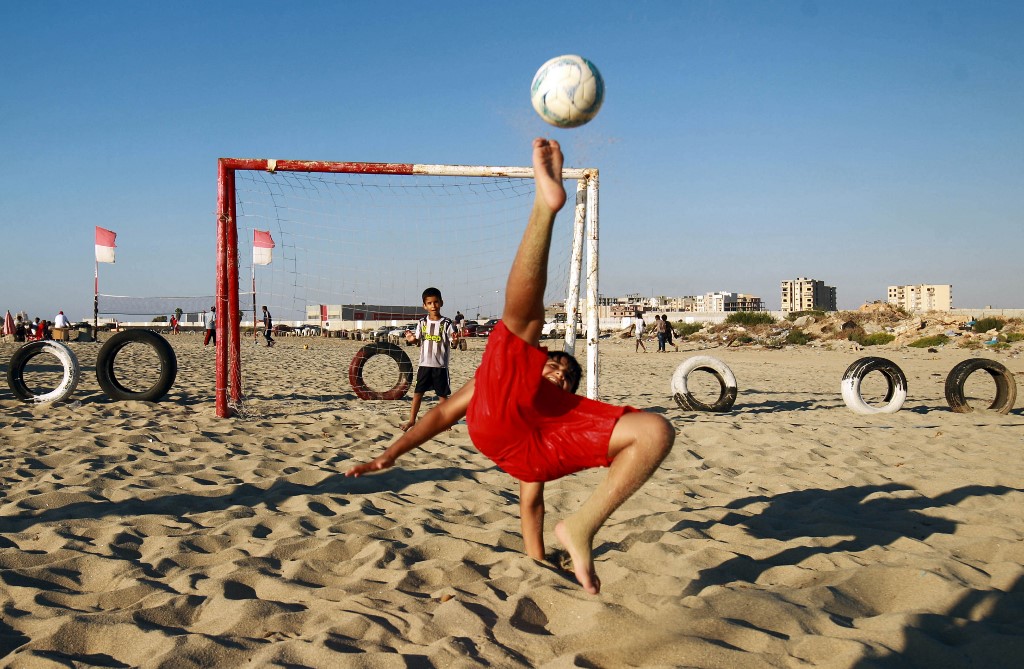A boy kicks a ball while shooting at a football net along a beach in Libya's eastern coastal city of Benghazi on August 22, 2020. (AFP/Abdullah DomaP)