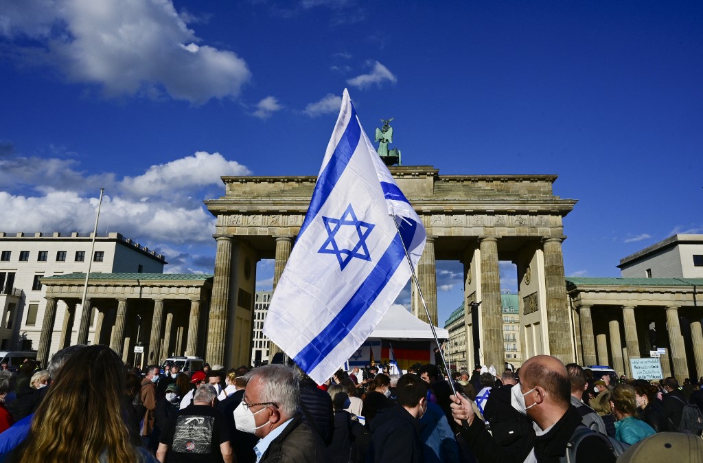 A participant waves an Israeli flag in front of Brandenburg Gate during a rally to express solidarity with Israel in Berlin on 20 May 2021 (AFP)