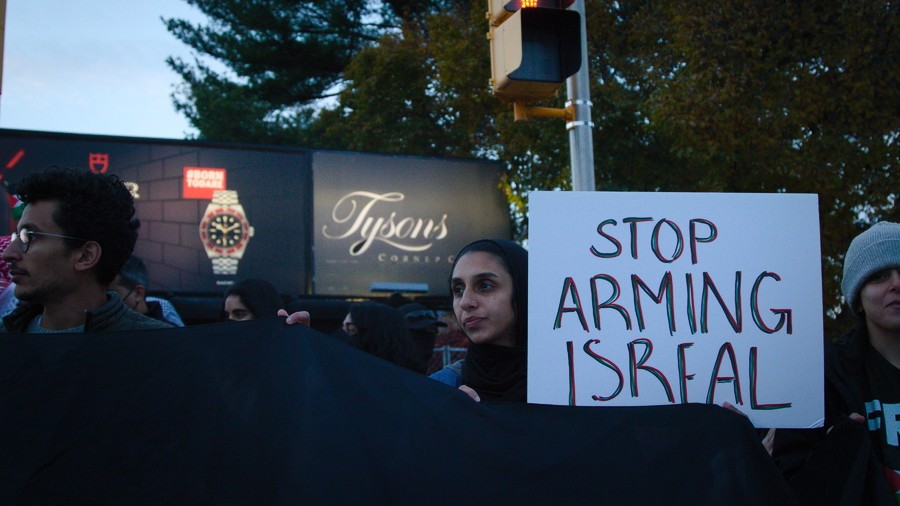 A pro-Palestinian demonstrator holds up a poster reading "Stop Arming Israel" outside the Tyson's Corner Center in northern Virginia on 24 November 2023.