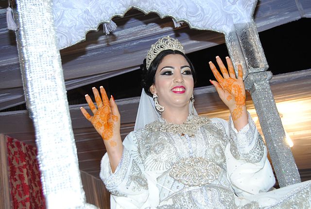 Une mariée montre ses mains décorées au henné (Wikimedia Commons)