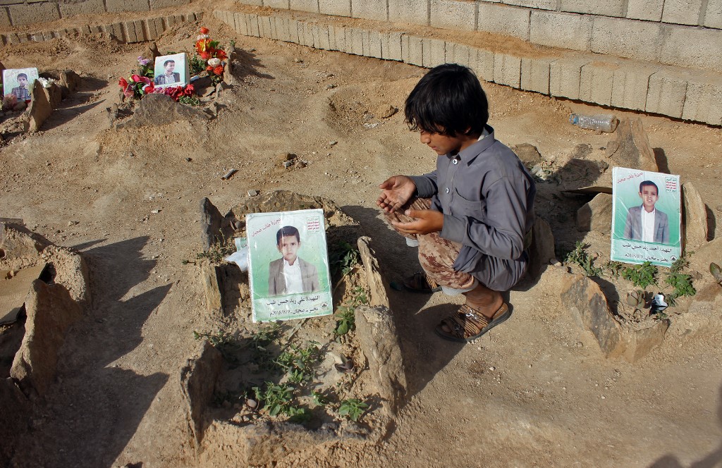 Un enfant yéménite prie devant la tombe d’un écolier tué lorsque son car a été attaqué par la coalition dirigée par l’Arabie saoudite en août 2018 (AFP)
