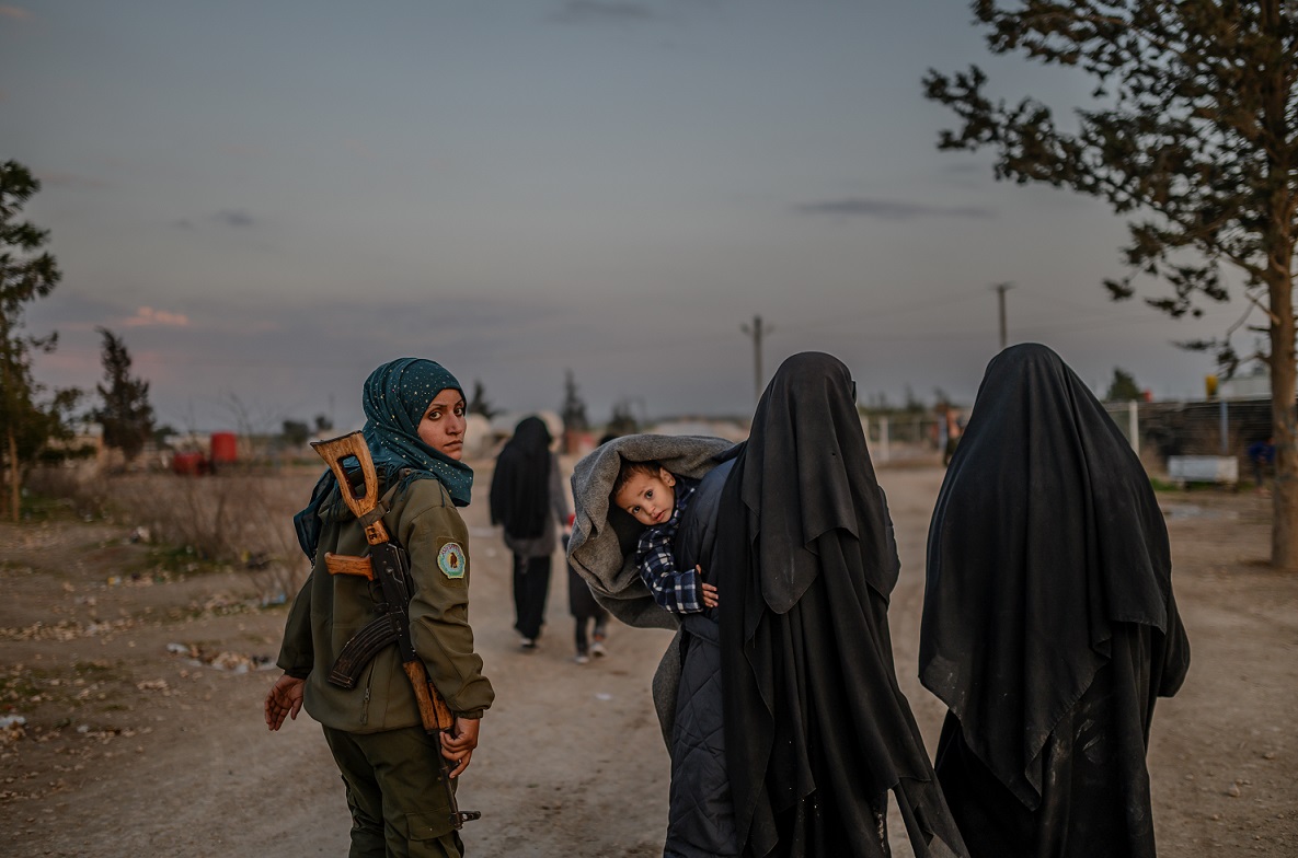 Women suspected of belonging to IS walk in al-Hol camp under the guard of an SDF fighter on 17 February 2019 (AFP)