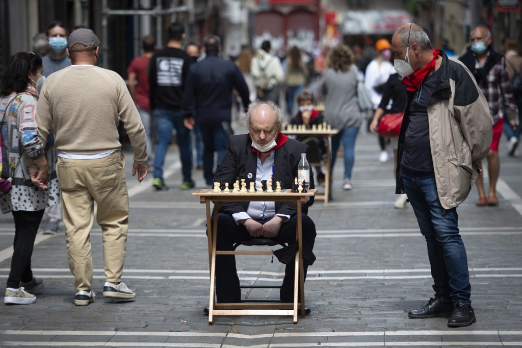 Two men ponder over a chessboard in Estafeta street in Pamplona during the "Chess Run" tournament on July 14, 2021. 