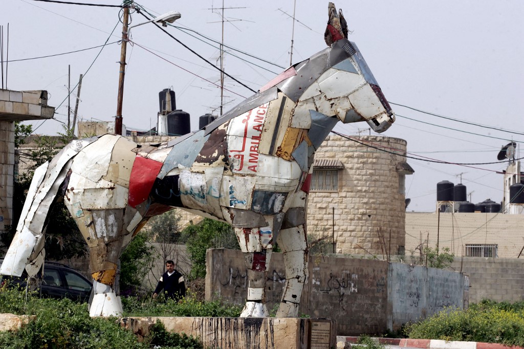 Un Palestinien marche le 11 mars 2010 près d’une sculpture de cheval réalisée à partir des restes de voitures palestiniennes détruites par l’armée israélienne lors d’une opération à grande échelle dans le camp de réfugiés de Jénine, en Cisjordanie (AFP/Saïf Dahlah)