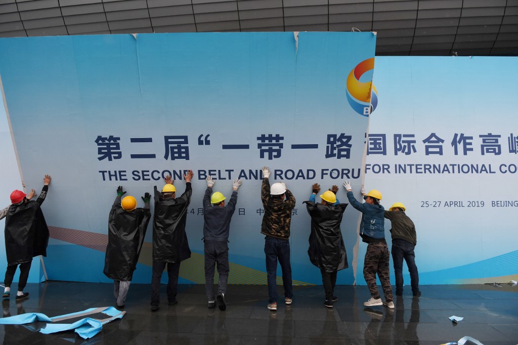 Des ouvriers retirent un panneau promouvant l’Initiative route et ceinture à l’extérieur d’un forum à Beijing, le 27 avril (AFP)