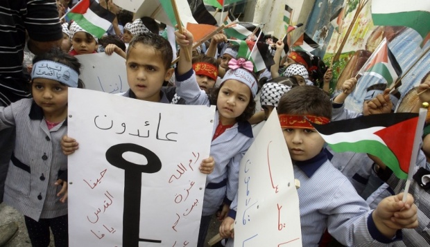 Palestinian children hold up pictures of keys, symbolising the homes they lost (AFP)