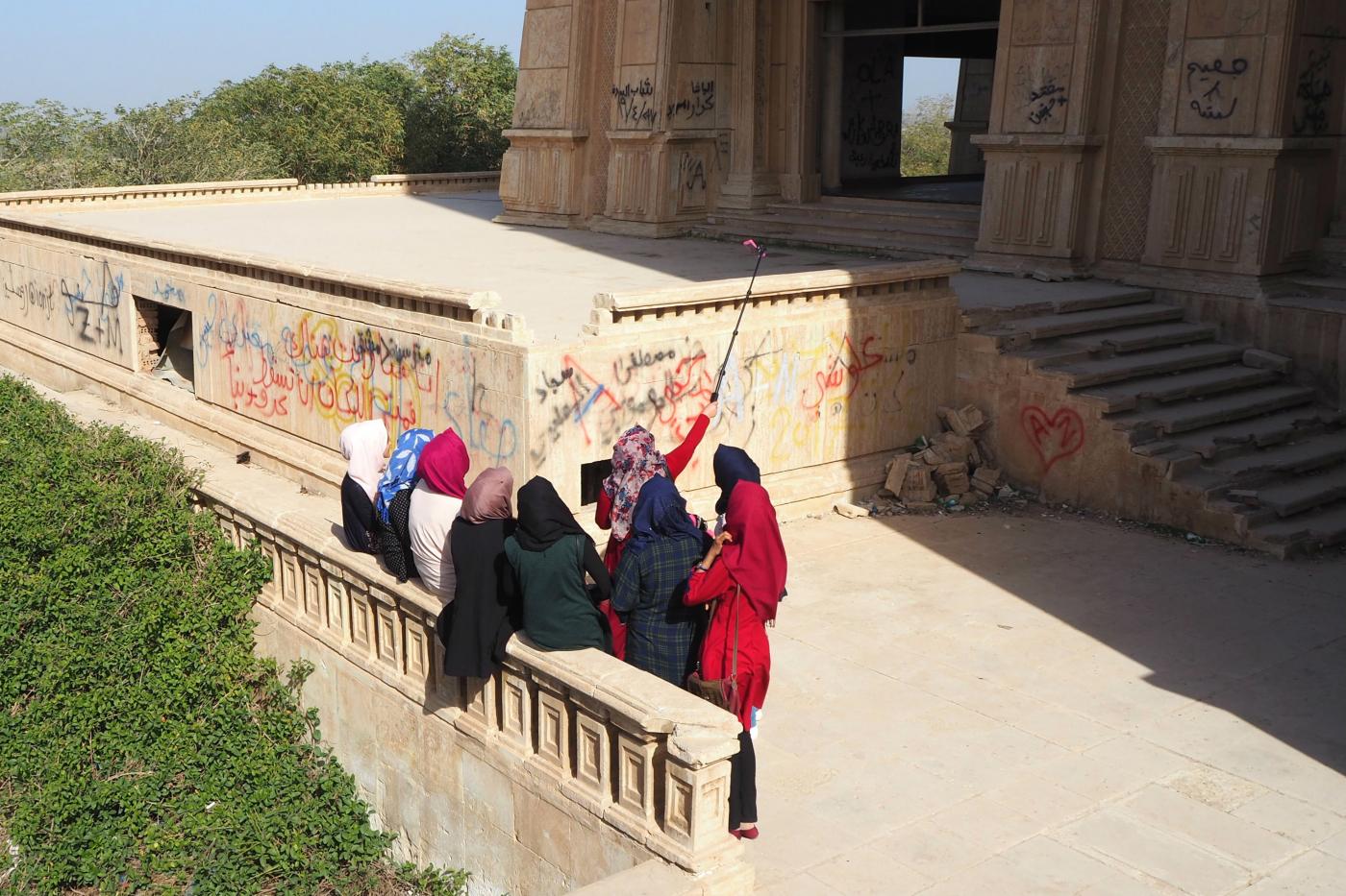 Des jeunes femmes posent pour des selfies devant le palais d’été de Saddam Hussein à Babylone (MEE/Tom Westcott)