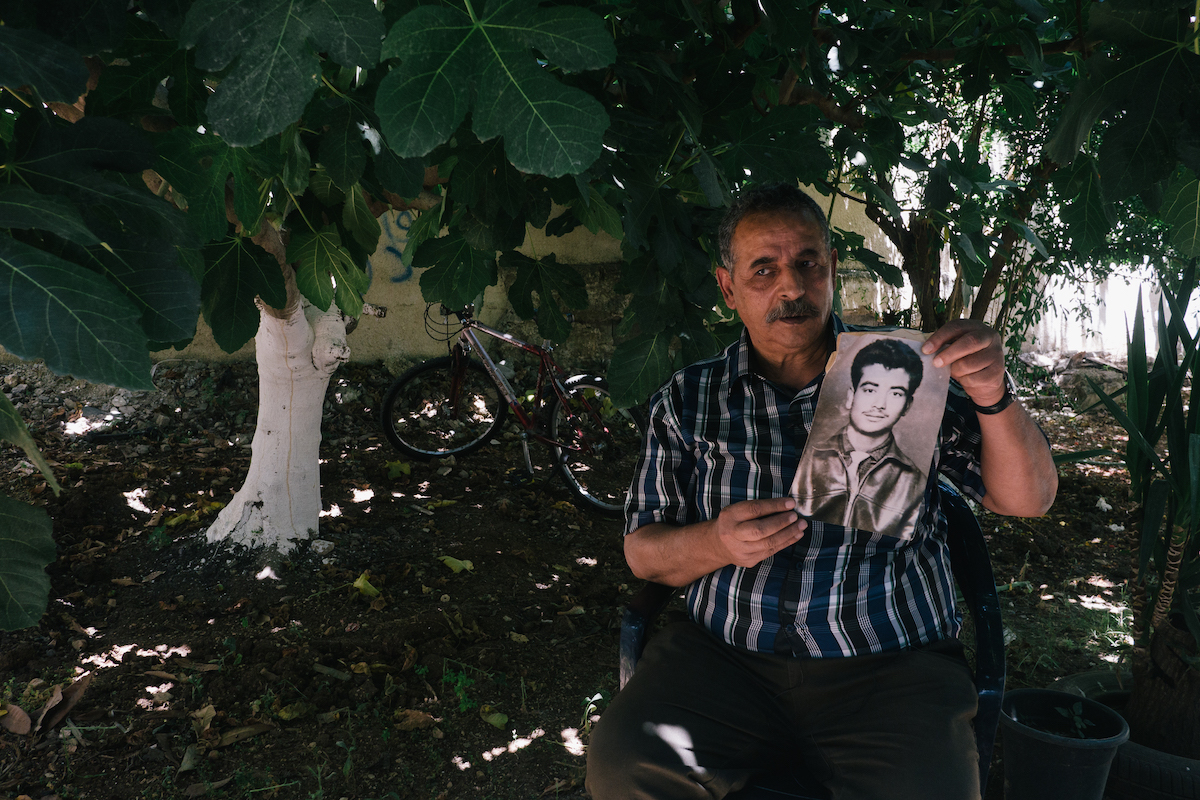 Hassan Dawleh holds a portrait of his brother Anis, who died in an Israeli prison 
