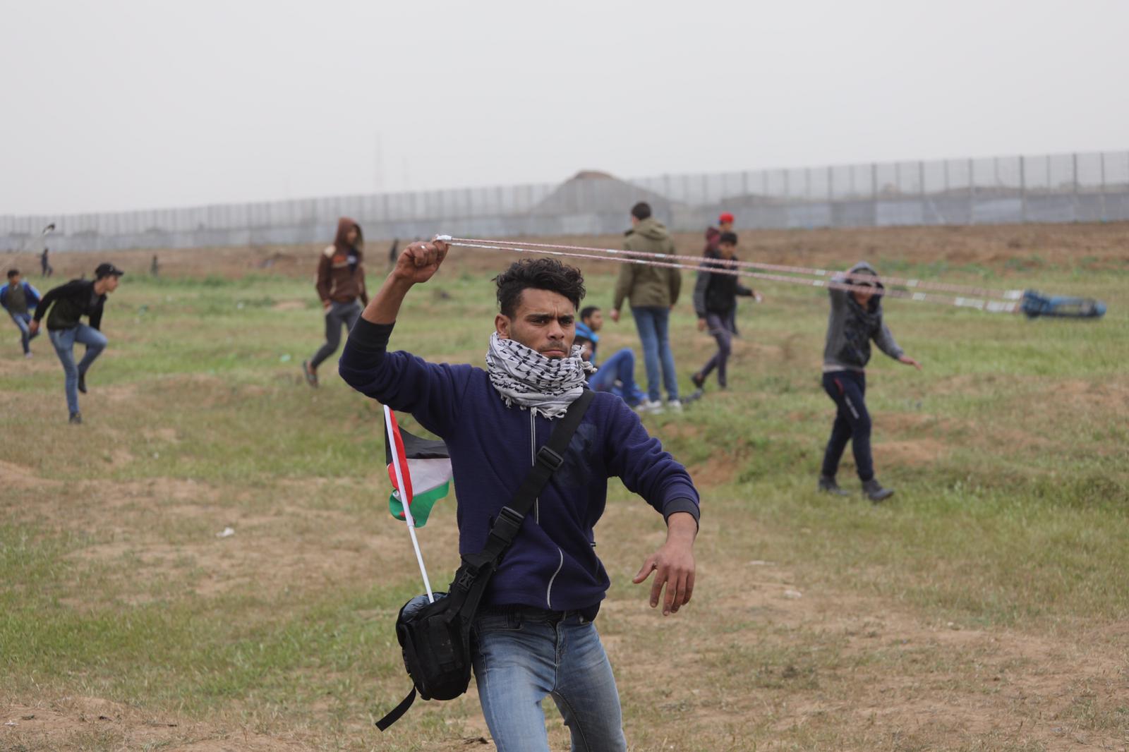 A Palestinian protester throws a rock in Gaza's Malaka (MEE/Mohamed Asad)