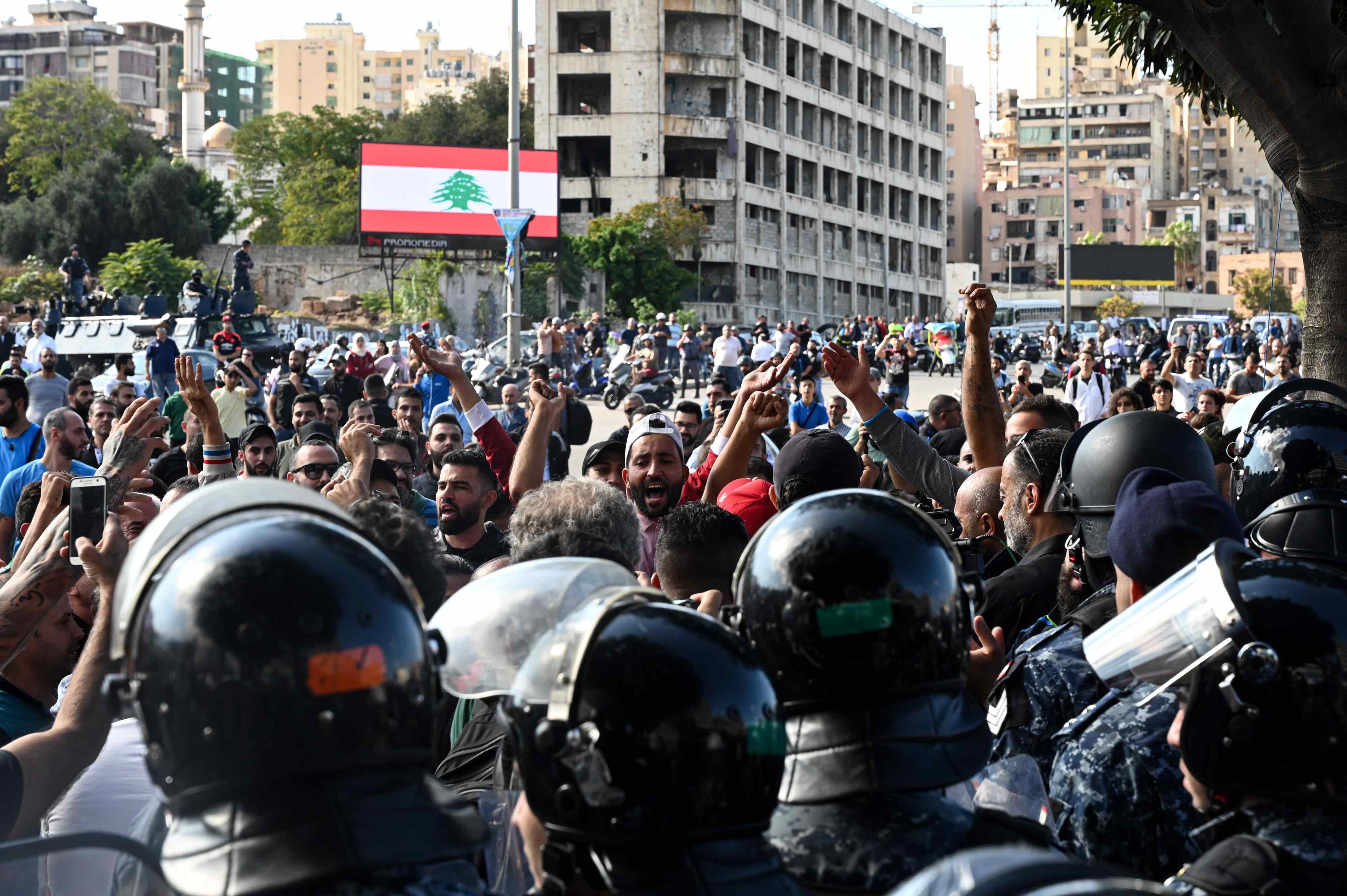 Un groupe de jeunes hommes, encadrés par la police anti-émeute, chante en faveur du président du Parlement, Nabih Berry, le 29 octobre (MEE/Finbar Anderson)