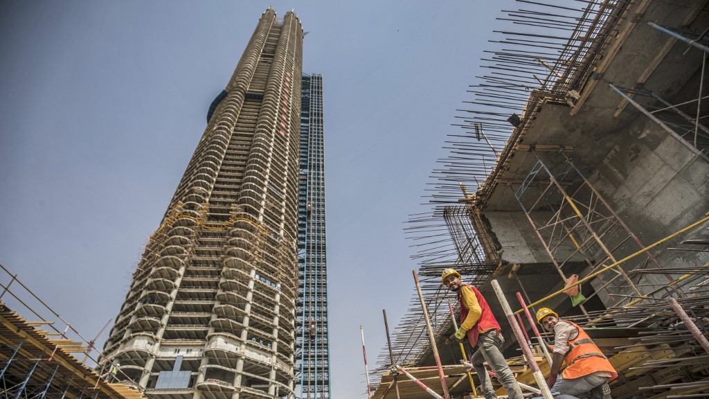 Workers build a skyscraper as part of Egypt’s new administrative capital mega-project east of Cairo on 3 August 2021 (AFP)