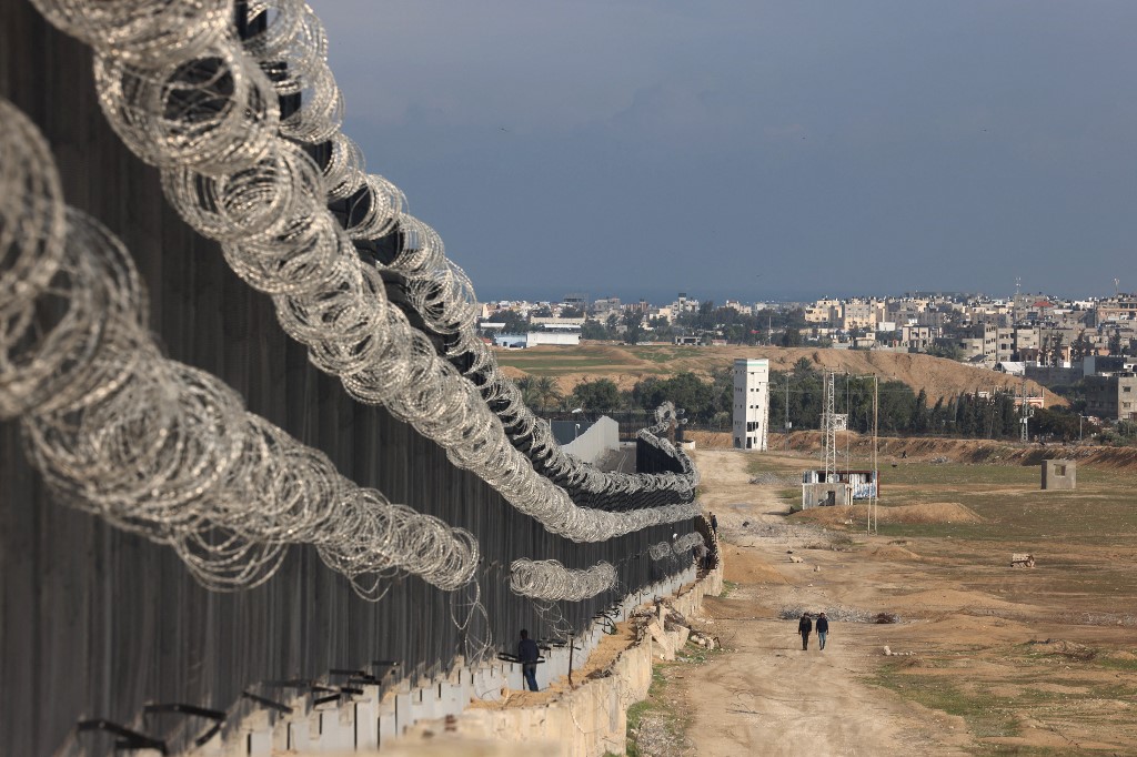 Displaced Palestinians walk next to the border fence between Gaza and Egypt, on February 16, 2024 in Rafah