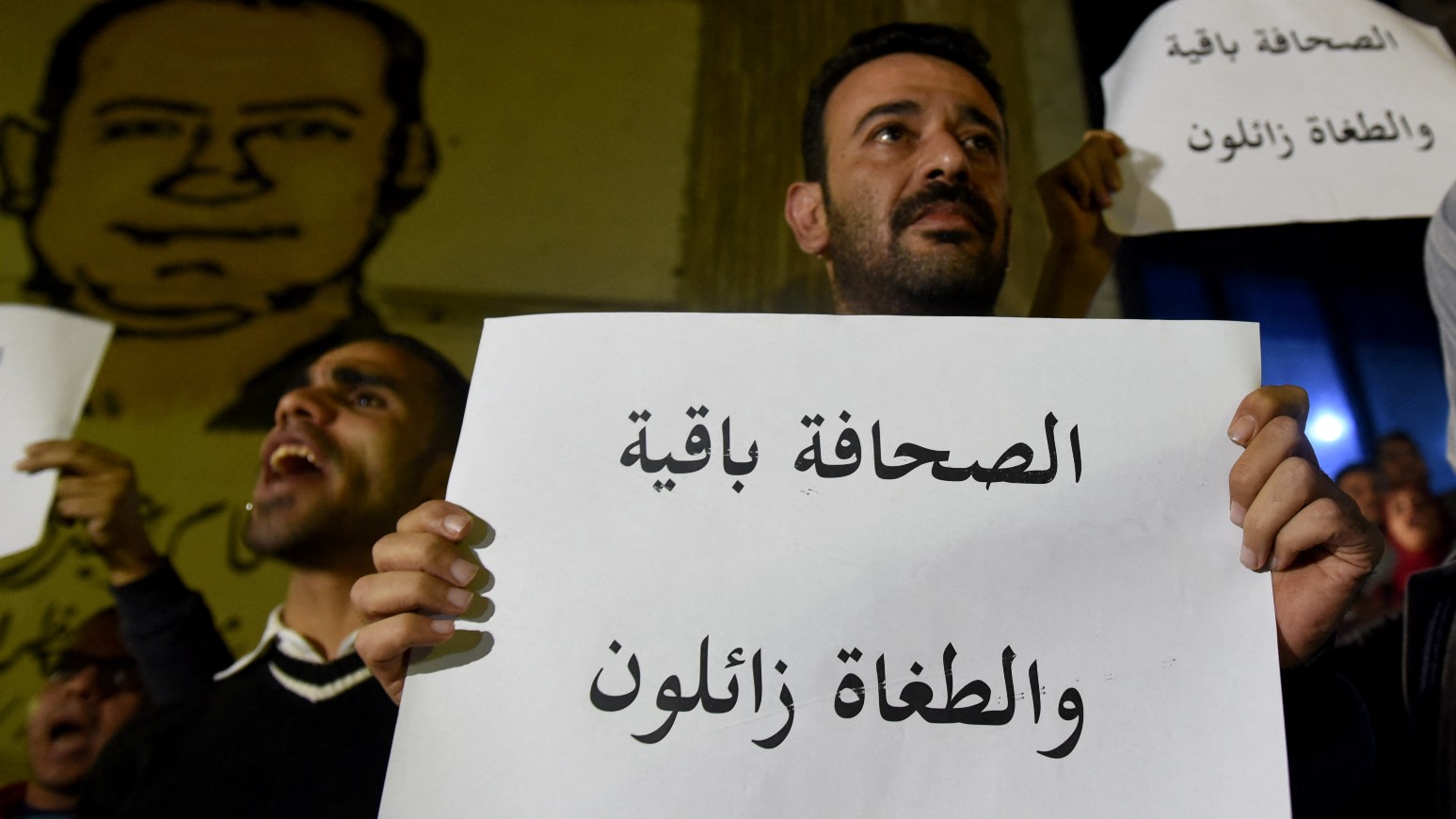 A journalist carries a placard which reads in Arabic 'Journalist is staying and the tyrants are on the demise' in front of the Journalists' Syndicate in Cairo on November 19, 2016