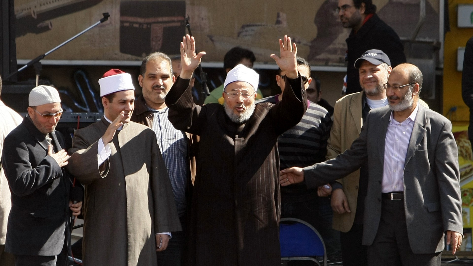 Egyptian-born Muslim cleric, Sheikh Yussef al-Qaradawi (C), greets the crowds as he stands on a stage before delivering the Friday prayer sermon at Cairo's central Tahrir Square on February 18, 2011 
