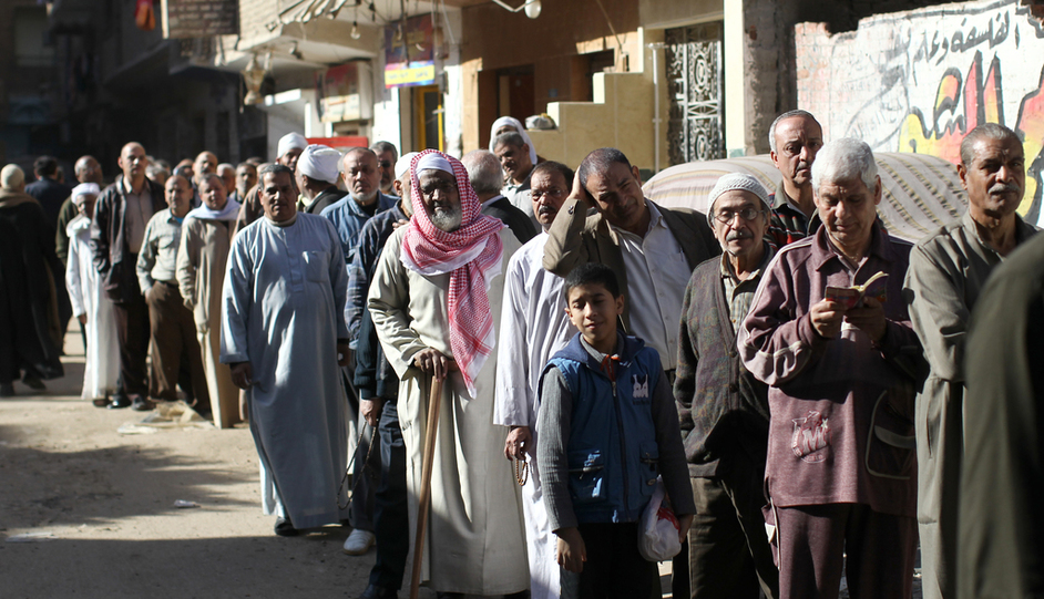 Egyptian men queue outside a polling station during the second round of a referendum on a new draft constitution in Giza, south of Cairo, on 22 December, 2012 (AFP)