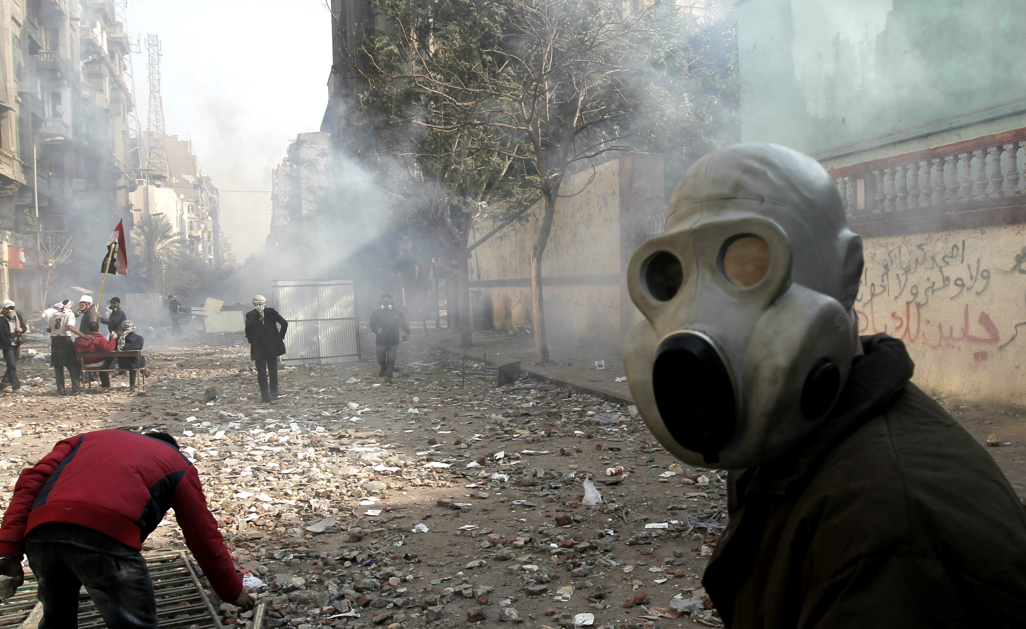 An Egyptian protester protects his face from tear gas during clashes with riot police near Tahrir Square, Cairo, in November 2011 (AFP)
