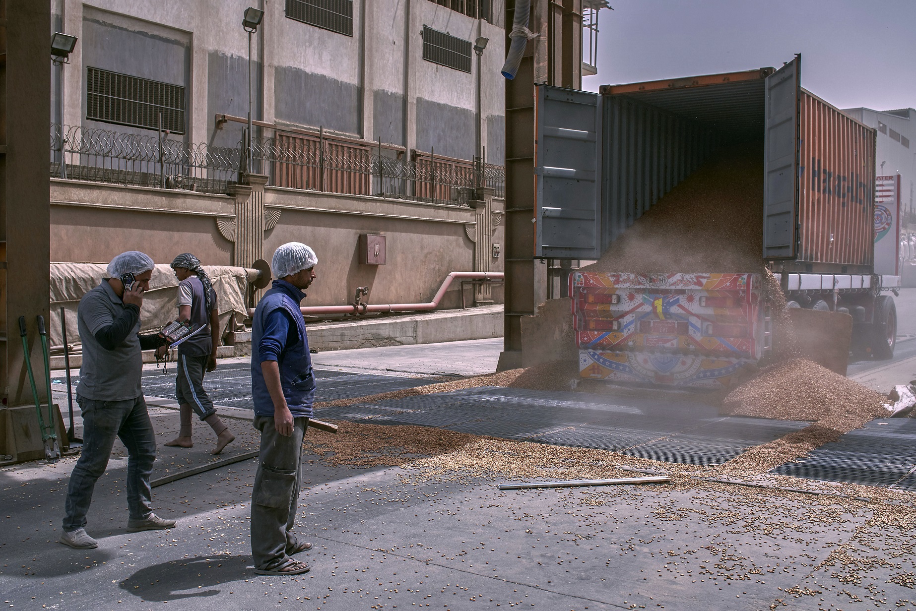 Un conteneur d’expédition contenant 25 tonnes de fèves est ouvert et des millions de graines sont déversées dans un silo, dans la zone industrielle d’al-Obor au Caire, le 9 avril 2019 (MEE/Hamada Elrasam)