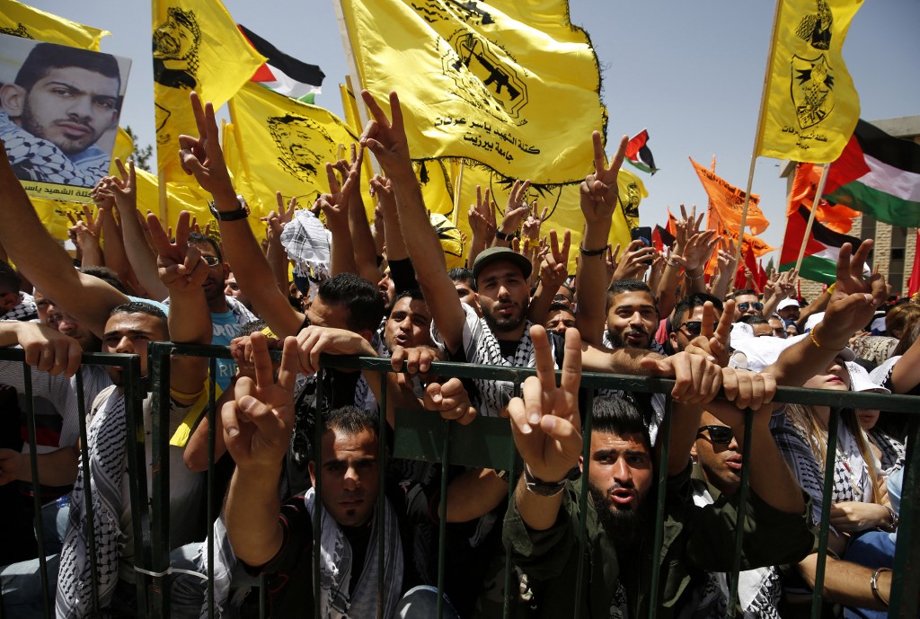 Palestinian students supporting the Fatah movement wave their flags during the student election campaign at Birzeit University on 26 April 2016 (AFP)