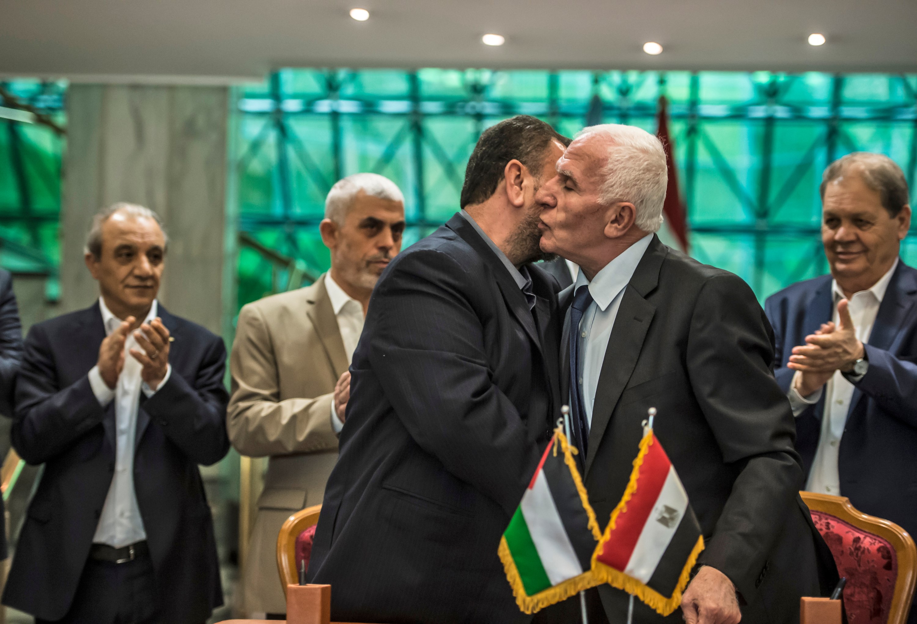 Azzam al-Ahmad du Fatah (à droite) et Saleh al-Aruri du Hamas s’embrassent après la signature d’un accord de réconciliation au Caire, le 12 octobre 2017 (AFP)