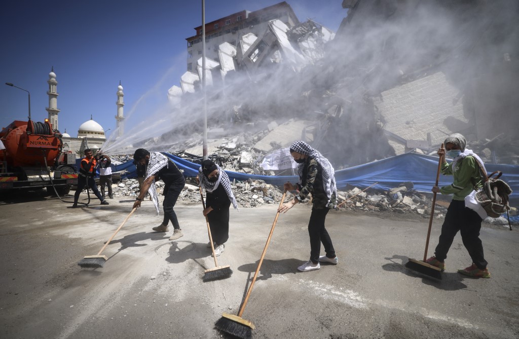 Palestinian volunteers and municipal workers clear rubble from Israeli air strikes in Gaza City on 25 May 2021 (AFP)