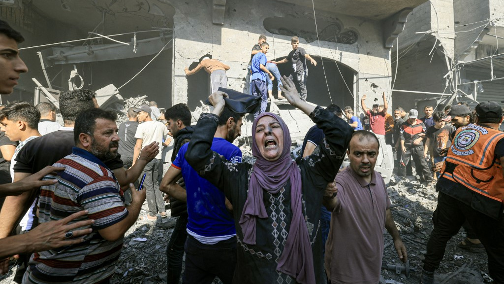 People search through the rubble of a building after an Israeli air strike in Khan Younis, Gaza, on 17 October 2023 (AFP)