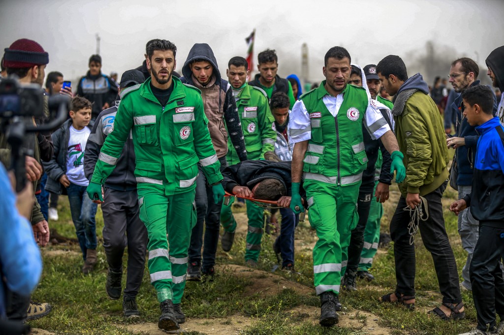 Palestinian paramedics carry away a man on a stretcher after being hit during clashes with Israeli forces following a demonstration marking the first anniversary of the "March of Return" protests, near the border with Israel east of Gaza City on March 30, 2019. 