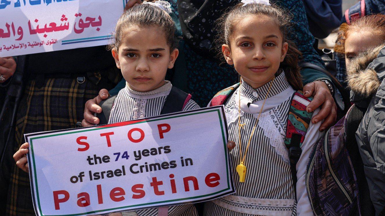 Des enfants palestiniens brandissent des pancartes pour réclamer le même soutien international pour les Palestiniens contre Israël que pour les Ukrainiens contre la Russie, le 7 mars 2022 à Gaza (AFP)