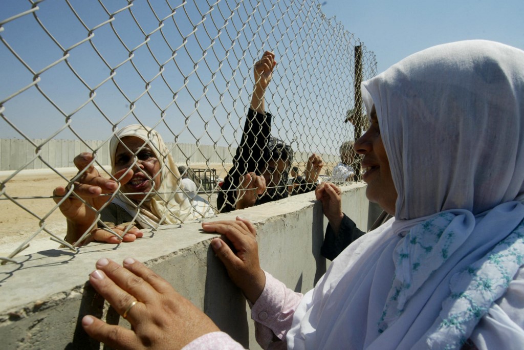 A Palestinian woman from Gaza holds the fence of the Philadelphi Corridor as she talks to a relative standing in Egyptian Rafah 12 September 2005 (AFP)