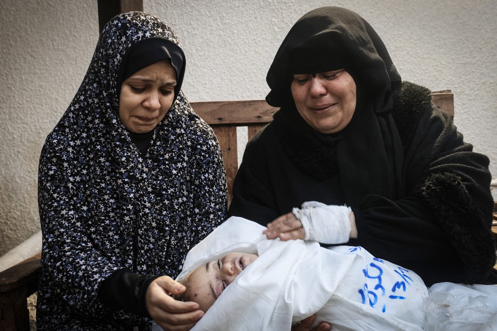 Relatives mourn Muhannad Ashour, the youngest of victims from the same family killed in Israeli bombardment on 14 December 2023, upon identifying his body at Najar hospital in Rafah (AFP)