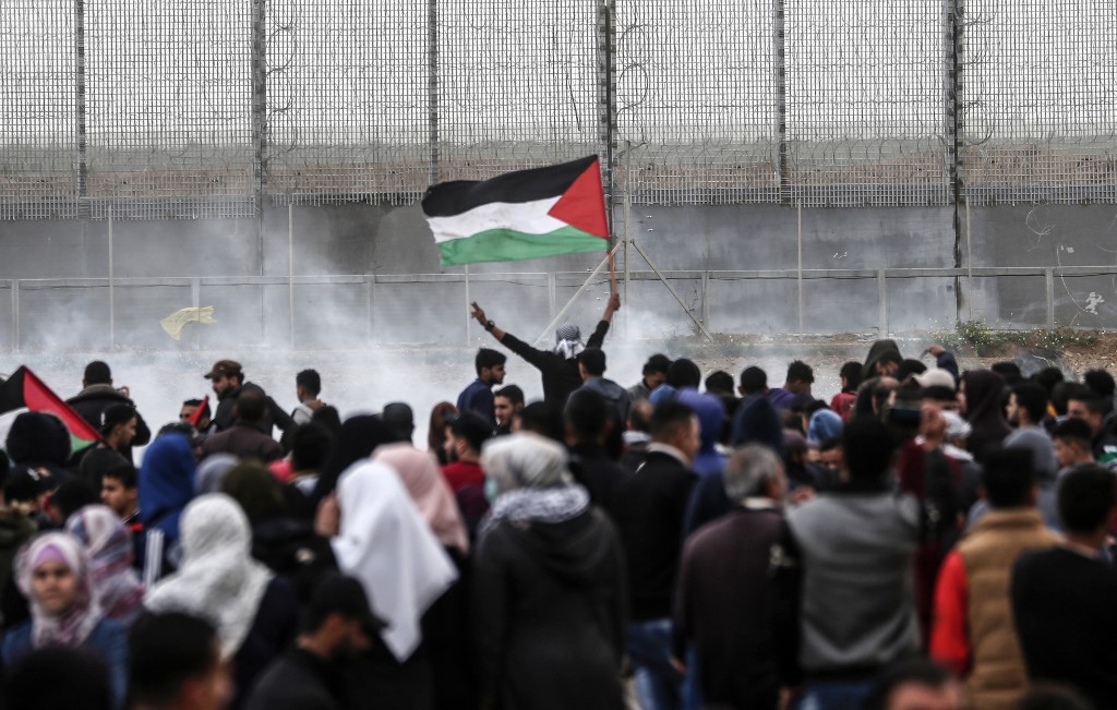 A Palestinian waves the national flag during a protest in Gaza on 30 March (AFP)